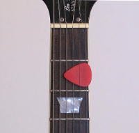 A photo of a guitar pick that is being kept between the strings